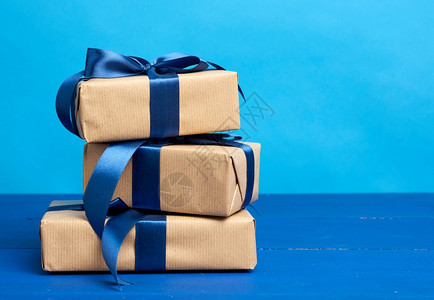 包在着棕色克拉夫纸的盒装礼物中并用蓝色背景的丝带捆绑生日圣诞节和影印空间的庆背景图片