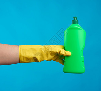 黄色橡皮手套上装有黄色橡胶手套的绿塑料瓶有清洁剂用于洗碗和家里的东西蓝底物品图片