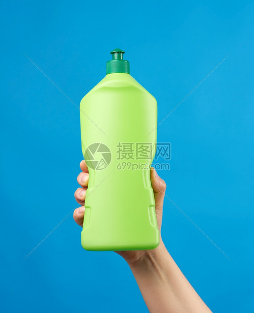 手里拿着绿色塑料瓶有洗涤剂用于碗和家里的东西蓝底物品图片