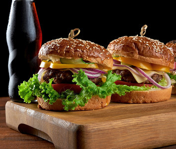 美味的汉堡包括炸牛肉切菜番茄生和洋葱烤白面条和芝麻种子图片
