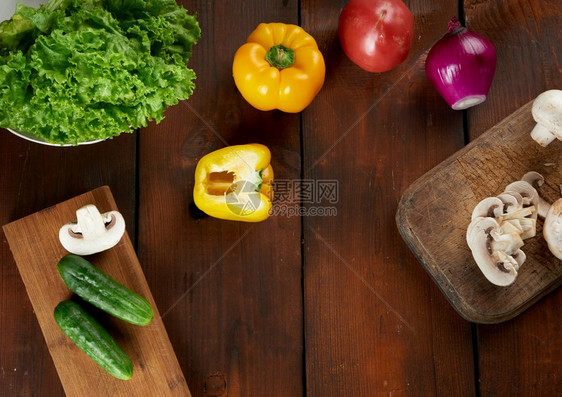 生蘑菇红和黄胡椒绿生菜和紫洋葱棕色木制桌上的番茄烹饪用料图片