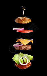 经典芝士汉堡的飞食成分芝麻包洋葱圈番茄片和黑色背景的多汁烧烤切片快餐图片