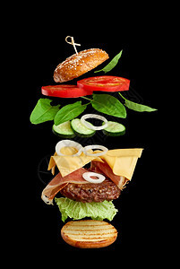 美味的芝士汉堡麻种子包番茄洋葱绿色生菜黑底奶酪三明治层图片