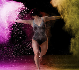 身穿黑色泳装和运动身材穿黑色运动服的美女穿着黑色面粉黄云黑背景面粉在跳舞图片