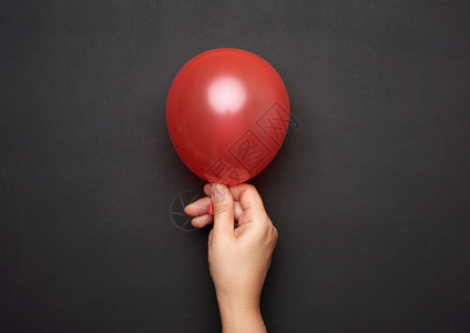 科技红女手握着一个膨胀的红气球在黑色背景上关闭背景