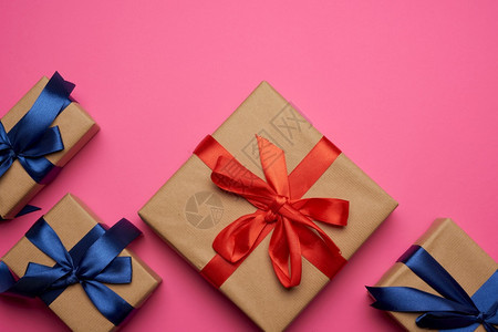 包裹在棕纸上绑红和蓝弓粉背景的礼品文字场所图片