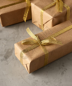 包裹在棕色纸上的长方形盒子绑上丝带绸有弓灰色背景的礼物关上图片