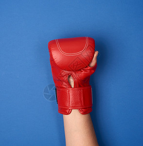 蓝背景女手上的红皮拳套被抬起来图片素材