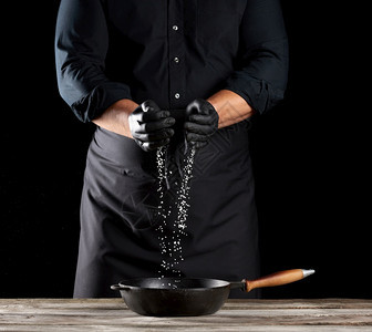 厨师的掌黑色背景男子身穿黑衬衫和围裙图片