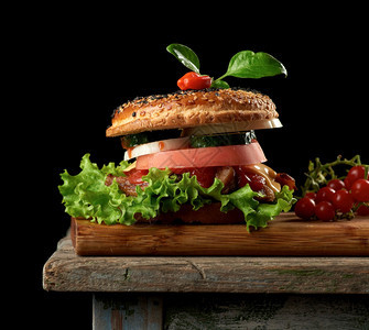 在木制棕褐色厨房板上加鲜肉绿生菜和番茄酱的芝士汉堡上面加辣椒图片