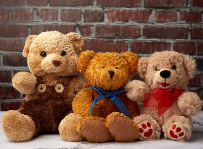 棕褐色泰迪熊坐在桌子上棕砖墙后面友谊概念图片