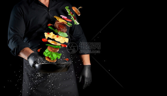 穿着黑色制服的男子拿着一个铁环煎锅配有上浮芝士汉堡成份麻奶酪番茄洋葱肉饼辣椒复制空间图片