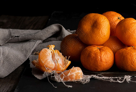 堆满的圆熟橙色芒达林在灰的纸巾上木桌图片