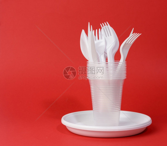 红色背景野餐式白色可支配塑料餐具板杯叉和刀图片