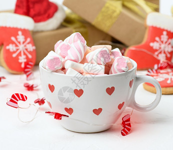 配有可和棉花糖的白陶瓷杯子放在礼物盒和圣诞玩具后面关门图片