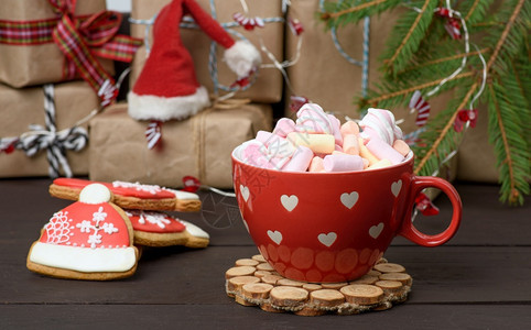 带有可和棉花糖的红瓷杯放在礼品盒和圣诞玩具后面图片