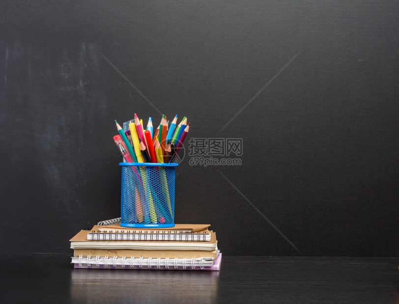 蓝色文具玻璃在空黑粉笔板的背面上带多色木笔的蓝文具玻璃回到学校的概念图片