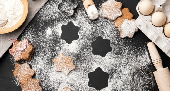在黑桌和配料上洒满糖粉的烤星形姜饼干最高视图图片