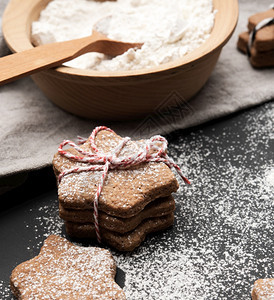 烤星形姜饼干涂满黑桌上的糖粉和配料图片