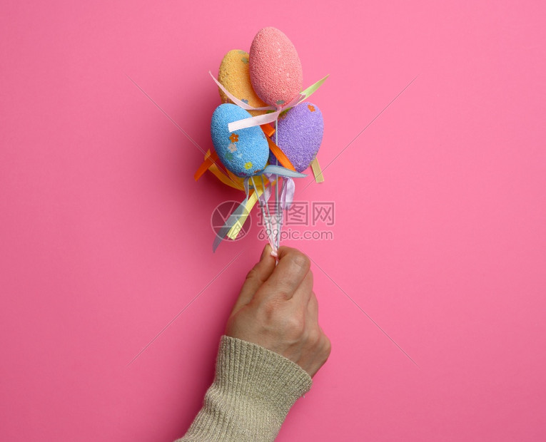 手拿着带装饰的鸡蛋粉色背景图片