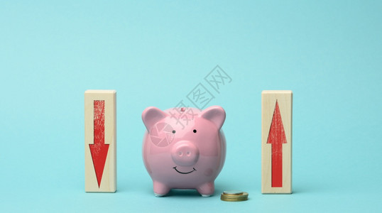 粉红色小猪银行和木制块红下和粉箭头银行利息波动收入下降和增加的概念背景图片
