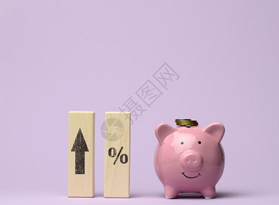 粉红色陶瓷罐头和顶有箭的木块增加银行存款利息高投资回报率大额销售利润的概念背景图片
