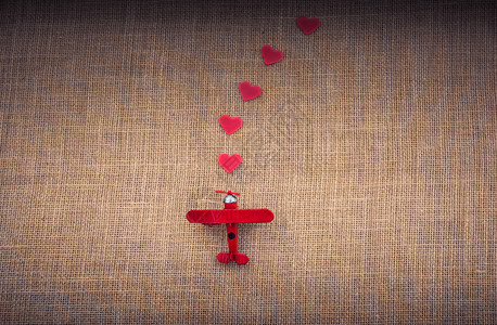 亚麻布上的玩具飞机前面摆着一排小爱心图片素材