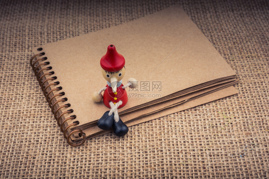 皮诺曹坐在笔记本上画布背景上图片