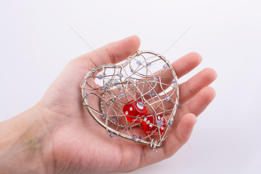 手握红骰子在白色背景的心形笼中
