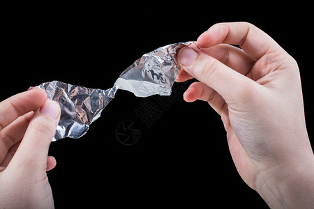 银衬用手在木背景上撕碎心脏形状的铝纤维背景