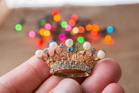 小皇冠与彩色的灯光紧握在背后图片
