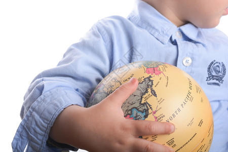 穿着蓝衬衫的婴儿拿着白色背景的球手握着一个地球图片