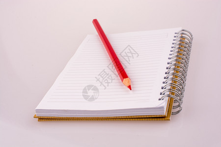 白背景的笔记本上彩色铅笔图片