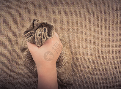 手握着用亚麻布制成的空小麻袋背景