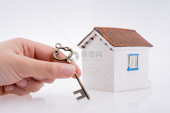 手拿着金钥匙握靠近白色背景的房子图片