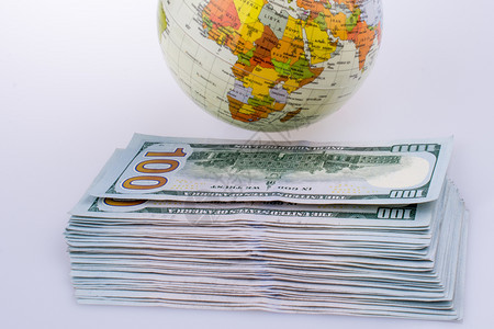 白色背景的模型地球旁边美元钞票图片