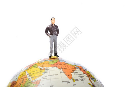 在白色背景上站地球顶端的男雕像图片