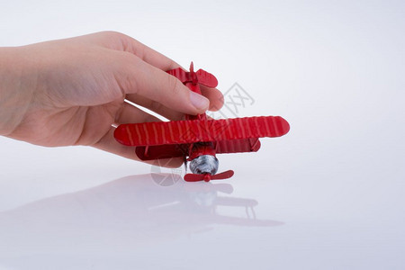 手持白色背景的红色玩具飞机图片