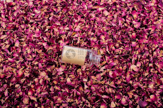 空瓶装在干玫瑰花瓣背景上图片