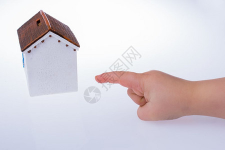 用小手指着一个白色背景的模范房子背景图片