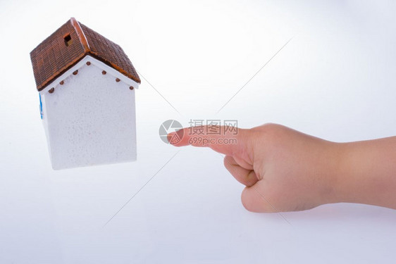 用小手指着一个白色背景的模范房子图片