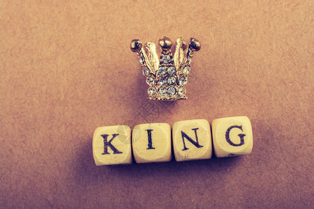 和国王在棕色上的措辞旁边微小模型王冠图片
