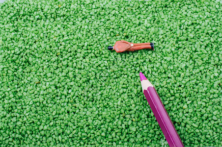 绿色沙质的人类模型和铅笔的微小雕像和绿色沙质的铅笔图片