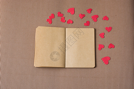 纸牌板上笔记本周围的纸红心图片