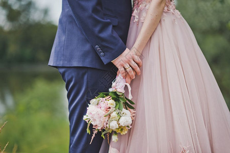 新娘和郎拿着一束花朵在新婚夫妇的手中一束花朵漫步在月经中图片