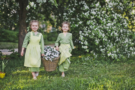 两个女孩拿着一篮花女朋友提了一个柳条篮子里面装着花用于花园装饰图片