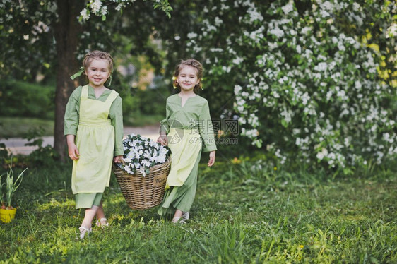 两个女孩拿着一篮花女朋友提着一个柳条篮子篮子里放着花用来装饰花园图片