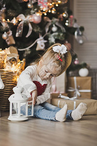 坐在圣诞树旁边的地板上一个小女孩坐在圣诞树下面带礼物7236图片