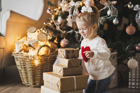 坐在圣诞树旁边的地板上一个小女孩坐在圣诞树下面带礼物7248图片