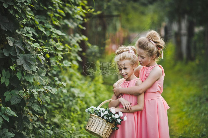 两个穿粉红色裙子的女朋友在花园里玩图片